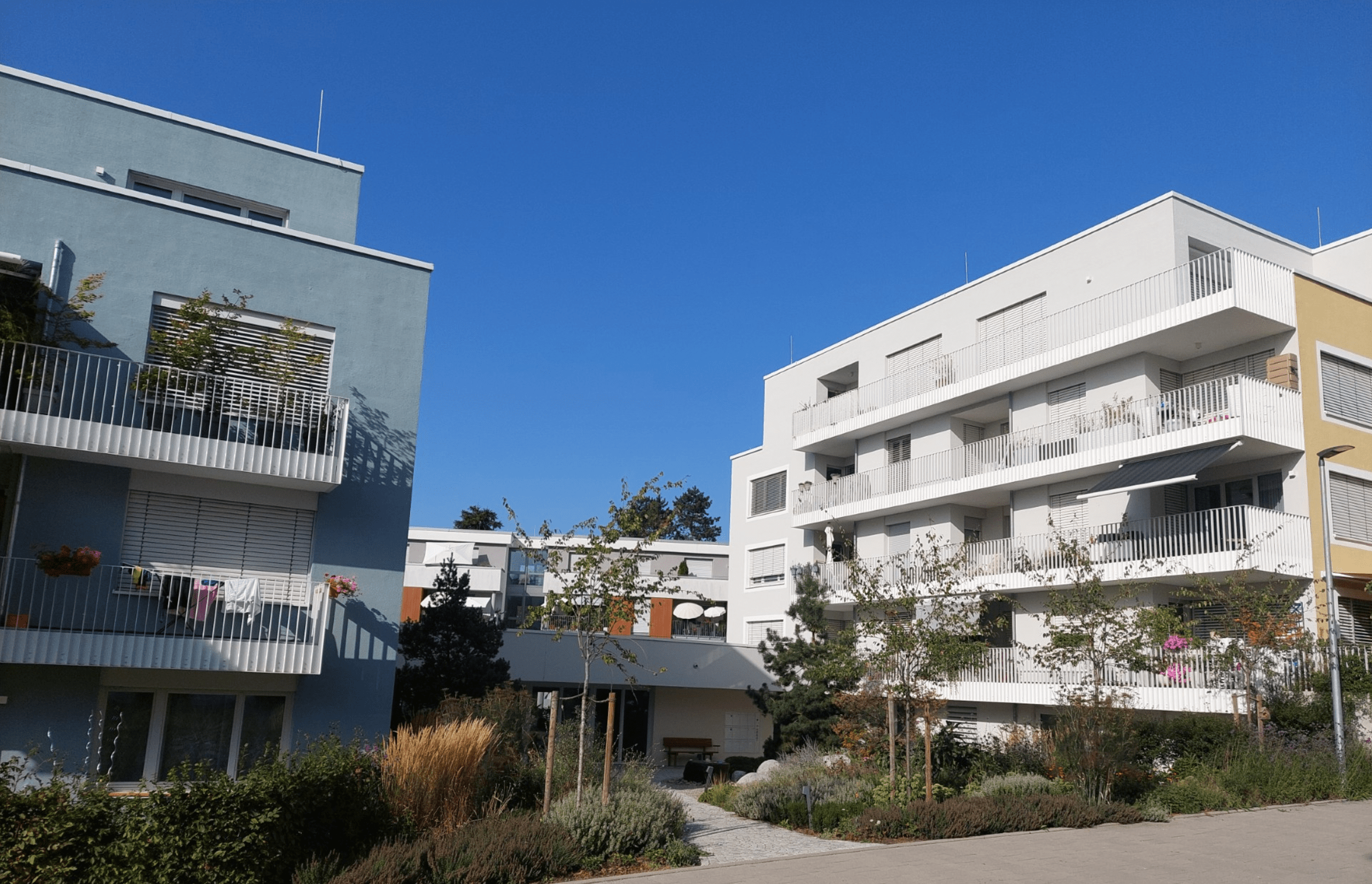 Ansicht eines modernen Wohnprojekts mit mehreren Häusern und gemeinschaftlichem Außenbereich